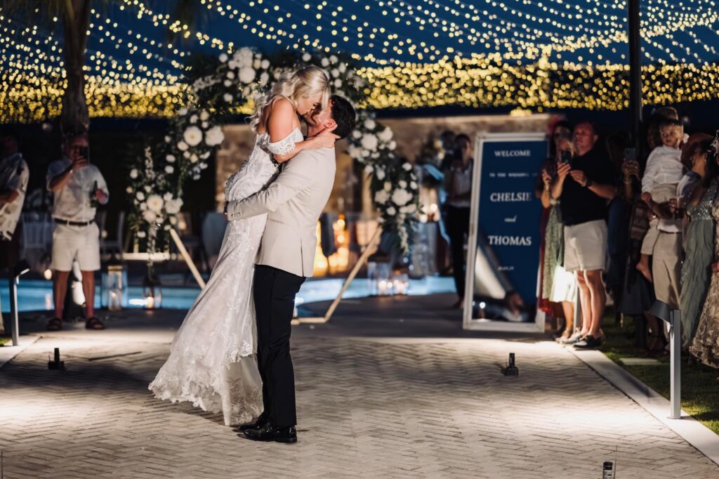 Bride and groom kissing under a roof of fairy lights