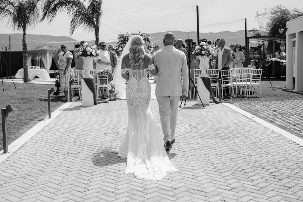 father and daughter walking down the isle at a wedding villa in Greece