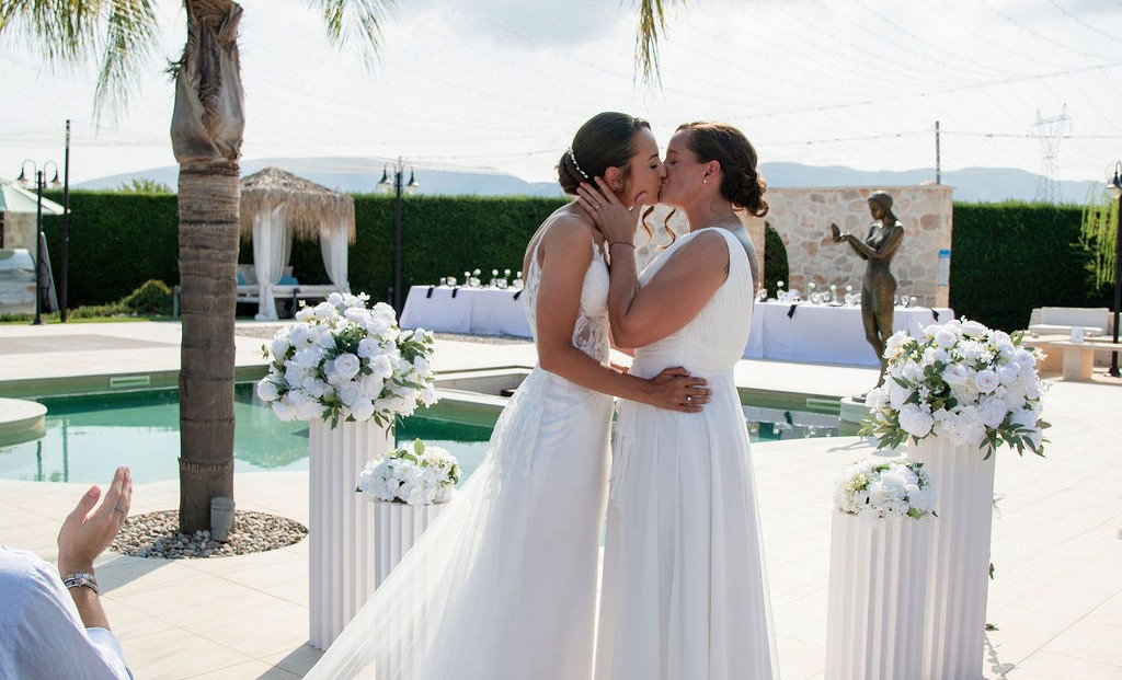 Two brides sharing their first kiss at their outdoor wedding ceremony in Zakynthos, Greece.